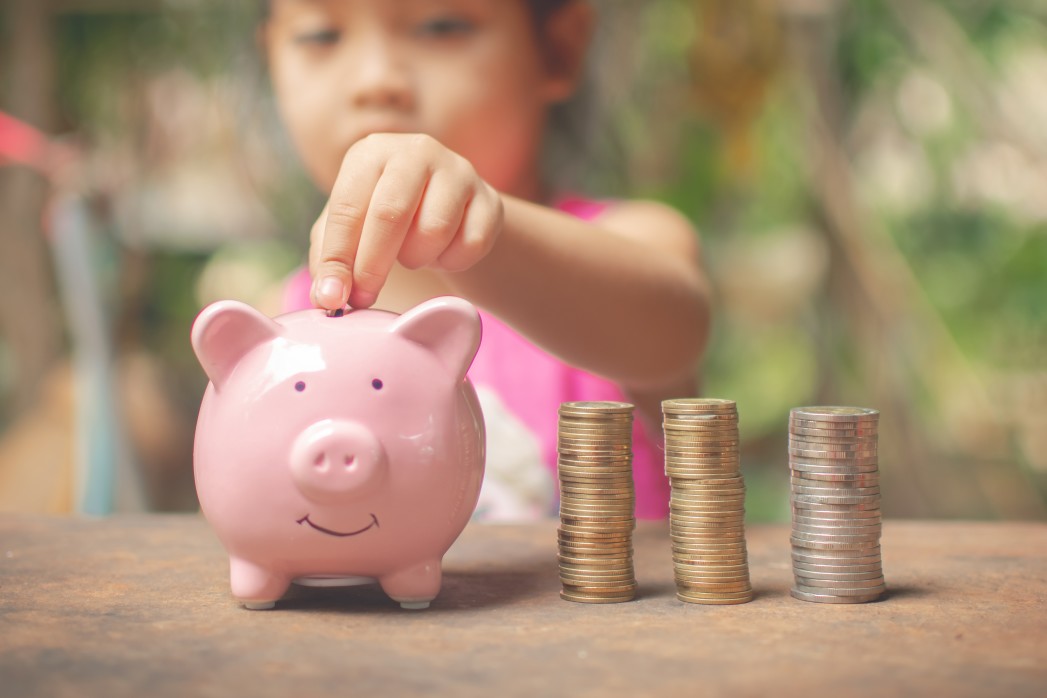 photo d'une petite fille mettant de l'argent dans sa tirelire cochon